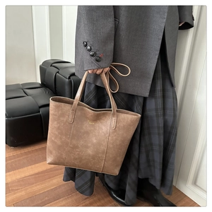 Detailopname van bruine vintage leren handtas met Fashion Bags tekst bij een modieuze outfit