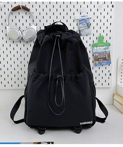 Detail of black drawstring backpack showing nylon texture and VOKOKO logo on pegboard