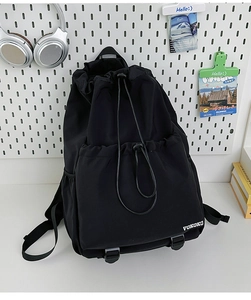 Detail view of the black drawstring backpack featuring dual front utility pockets and logo