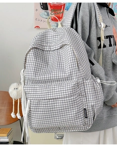 Detail eines karierten Canvas-Rucksacks mit Plüsch-Anhänger und Webetikett in der Schule