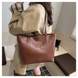 Detail van een bruine leren shopper met fijne textuur en gouden Fashion Bags-belettering