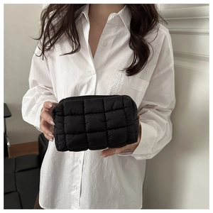 Detail showing the black quilted texture and checkerboard stitching of the soft makeup bag