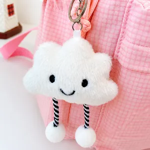 Close-up of cute white cloud plush keychain with smiling face on a pink checkered bag