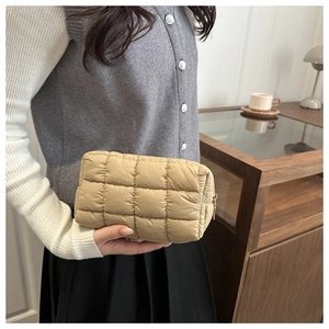 Close-up of khaki quilted makeup bag with square stitching and gold zipper detail