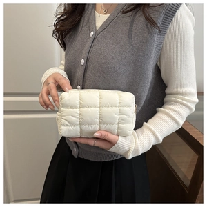 Close-up of quilted cream makeup bag with soft nylon padding and metal zipper