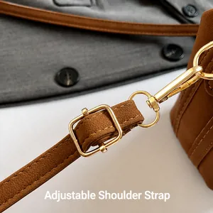 Detail of adjustable shoulder strap with golden metal buckle on brown leather bag