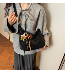 Sac bandoulière demi-lune noir avec breloques ourson porté par un mannequin