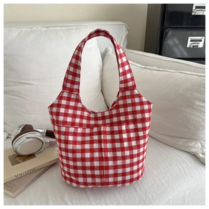 Detail der rot-weißen Gingham-Stofftasche mit Außentaschen auf einem weißen Sofa