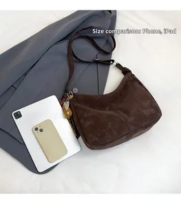 Sac bandoulière en daim marron foncé montrant sa grande capacité par rapport à un iPad