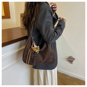 Détail du sac croissant en cuir mat marron foncé avec pendentif ours sur modèle