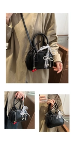 Dettaglio mini borsa nera con fiocco in pizzo, catena di perle e ciondoli a ciliegia