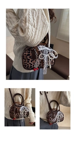 Dettaglio borsa leopardata con fiocco di pizzo bianco, perle e ciondoli ciliegia