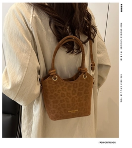 Détail du sac seau en daim léopard avec poignée nouée et lettrage doré chic