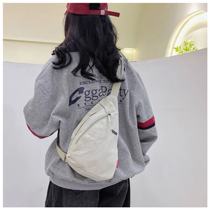 Back view of a cream nylon crossbody bag featuring a teardrop design and red side label
