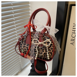 Dettaglio della mini borsa Boston leopardata con finiture in pelle rossa e ciliegia
