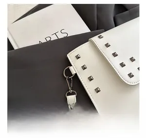 Detail of vintage metal fasteners and studs on white leather envelope clutch bag