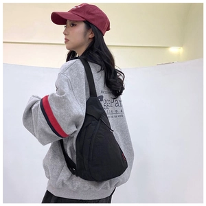 Close-up of black nylon crossbody bag featuring red side label and adjustable strap