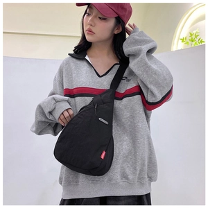 Close-up of minimalist black nylon chest bag with red FASHION label and adjustable strap