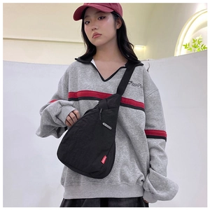 Close-up of black nylon crossbody bag with red FASHION label on casual female model