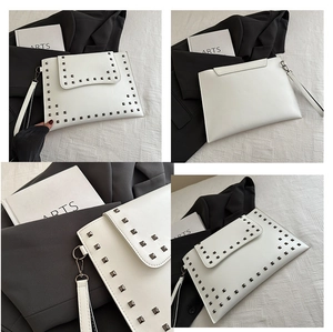 Detail view of a white envelope clutch bag with silver square studs and wrist strap