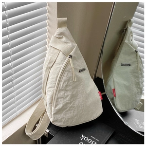 Detail of cream nylon crossbody bag with zipper pocket and silver logo plaque