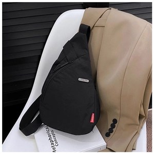 Detail view of a black nylon crossbody chest bag on a white chair with professional styling