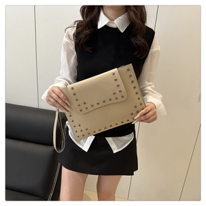 Close-up of beige rivet envelope clutch bag with silver studs and leather wrist strap