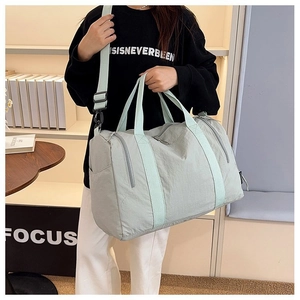 Detailed shot of large mint green nylon travel bag with crossbody strap and handles