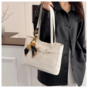 Close-up of white crocodile embossed tote bag with elegant silk scarf on handle