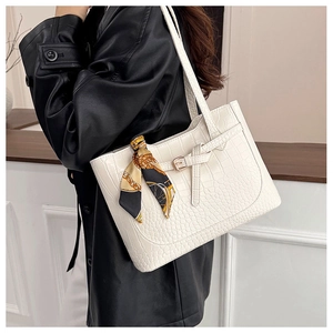 Close-up of white crocodile pattern tote bag with printed silk scarf and metal clasp detail