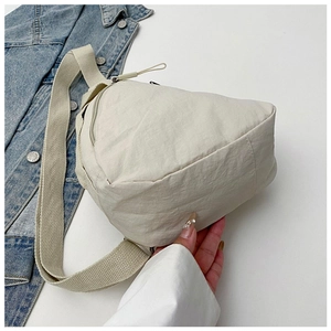 Detail of cream nylon chest bag featuring water-resistant fabric and thick strap