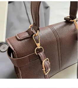 Detalle del gancho de metal dorado y cuero marrón texturizado en un bolso bandolera