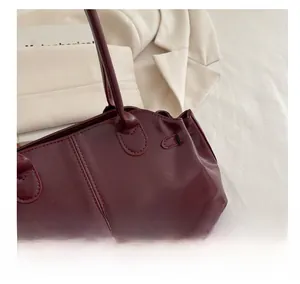 Close-up of burgundy oily faux leather surface and stitching on a large tote bag