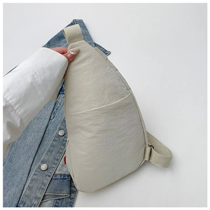 Detail of minimalist nylon crossbody bag featuring a front pocket and adjustable strap