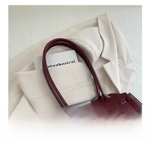 Detail view of burgundy wax leather tote texture and durable shoulder strap handles