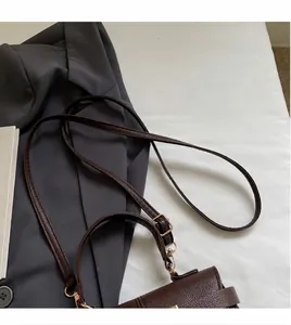 Detalle de la correa ajustable y los herrajes dorados en el bolso de cuero marrón oscuro