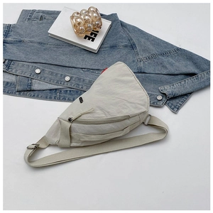 Flat lay of a beige nylon crossbody chest bag with adjustable strap and front pocket