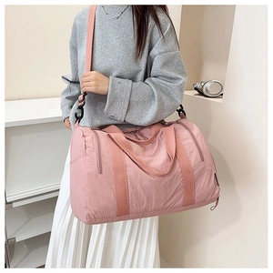 Pink nylon travel bag with adjustable strap shown in a minimalist lifestyle setting