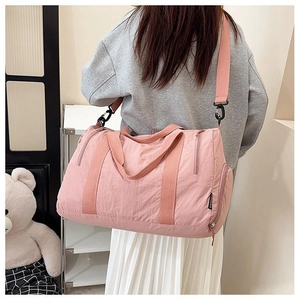 Detail of pink nylon gym bag showing adjustable strap and multi-pocket storage design