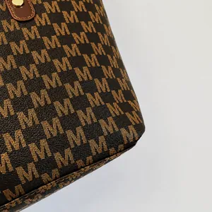 Vista macro del motivo monogramma marrone e del rivetto dorato sulla borsa tote