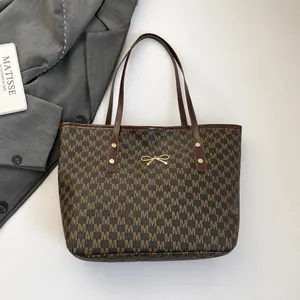 Dettaglio della borsa tote marrone con stampa monogramma M e fibbia a fiocco dorato