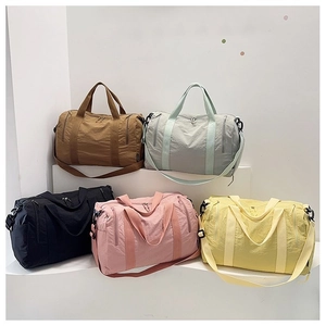 Five assorted colors of large nylon travel bags displayed on a minimalist white staircase