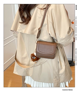 Close-up of brown textured leather crossbody bag featuring a cute plush bear charm