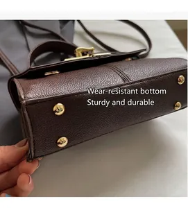 Detalle de la base del bolso en cuero marrón con cuatro pies de metal dorado protector