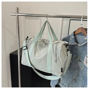 Close-up of mint green nylon sports bag with metal hooks and adjustable shoulder strap