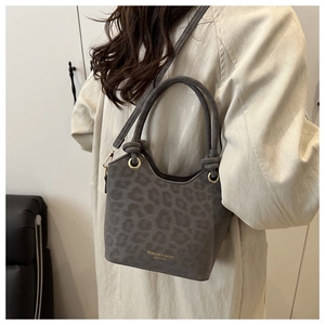 Close-up of leopard print shoulder bag featuring gold lettering and knotted handle