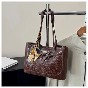 Detail of dark brown crocodile embossed tote bag with vintage scarf and metal buckle
