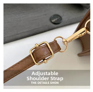 Detailed macro view of adjustable brown leather shoulder strap with gold metal buckle