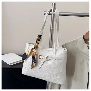 Close-up of white tote bag with crocodile texture and elegant printed silk scarf
