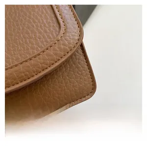 Close-up of brown litchi pattern leather texture and precise stitching on the small square bag